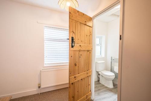a bathroom with a toilet and a wooden door at 10 Northgate, Beccles in Beccles