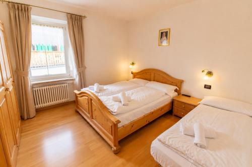 a bedroom with two beds and a window at Rossetti 3 camere by AMA Val di Fassa in Pozza di Fassa