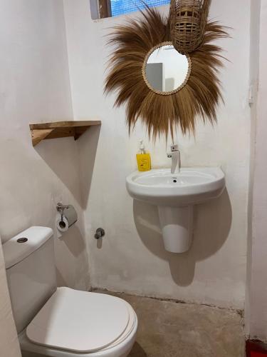 a bathroom with a toilet and a sink and a mirror at Mambo Leo Hostel in Paje