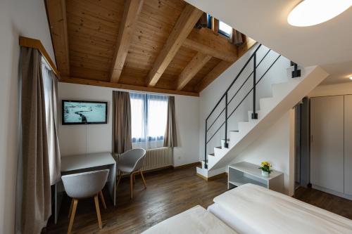 a bedroom with a bed and a desk and a staircase at Hotel Restaurant Alte Brauerei in Celerina