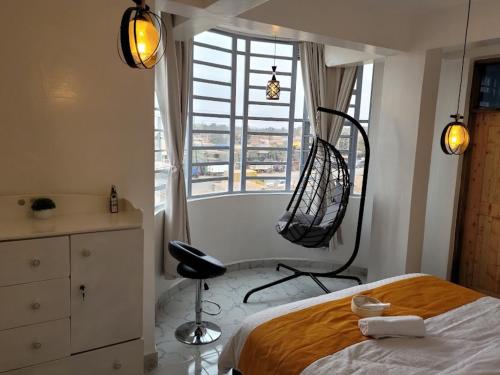 a bedroom with a bed and a chair and a window at KilimaVista Homes 1 bedroom apartment in Kimana