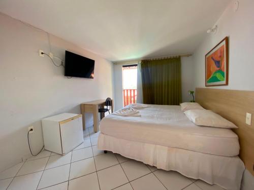 a hotel room with a bed and a television at Ponta Negra Palace in Natal