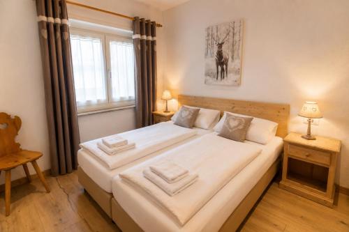 a large white bed in a room with a window at Appartamenti Col Rodella by AMA Val di Fassa in Campitello di Fassa