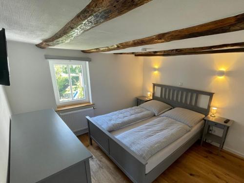 a bedroom with a bed and a table and a window at Gästeappartements Mechels in Wilnsdorf