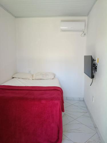 a white room with a bed with a red blanket at Pousada Caranguejo in Cairu