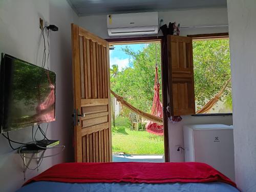 a bedroom with a bed and a window and a television at Pousada Caranguejo in Cairu
