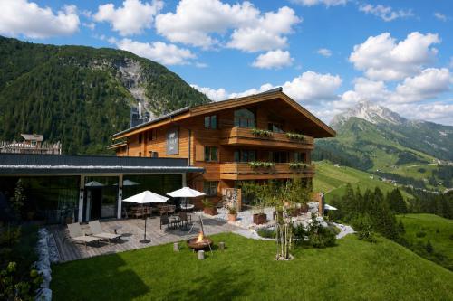 a house on a hill with mountains in the background at LUX ALP CHALET am Arlberg in Warth am Arlberg