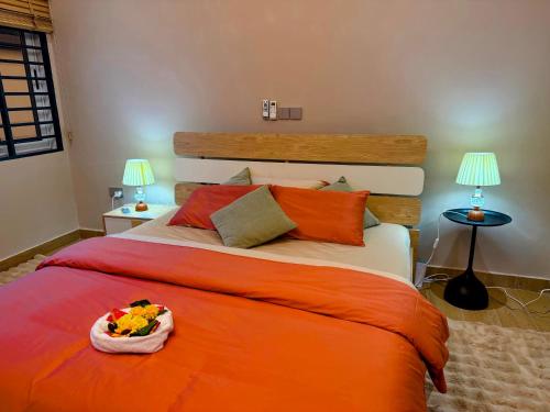 a bedroom with a large bed with an orange blanket at Leaves & Stones in Kwedonu