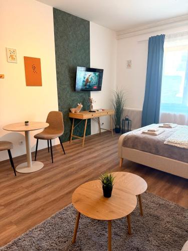 a living room with a bed and tables and a tv at Apartments Chloe - Top 3 in Hollabrunn
