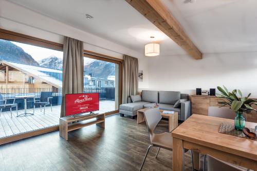 a living room with a couch and a tv and a table at AlpenParks Hotel & Apartment Orgler Kaprun in Kaprun