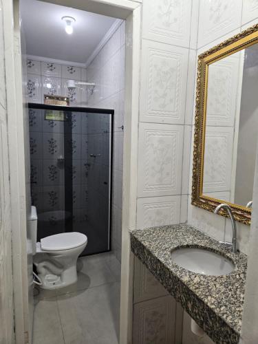 a bathroom with a toilet and a sink and a mirror at Casa de Charles in Piranhas