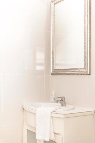 a white bathroom with a sink and a mirror at Julinas Guesthouse in Panorama