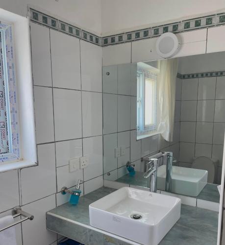 a white bathroom with a sink and a mirror at Bliss home in Watamu