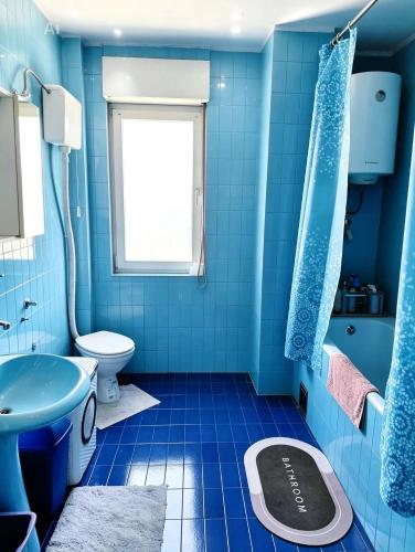a blue bathroom with a toilet and a sink at Kiwi house in Podgorica