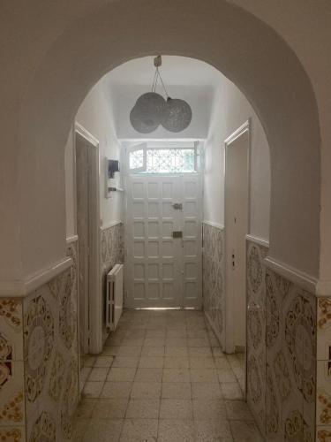 a hallway with a white door and a window at Nice house ideally located in Dar Tahar Zaouch