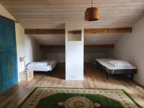 two beds in a room with wooden ceilings at Maison 8 personnes in Mézos