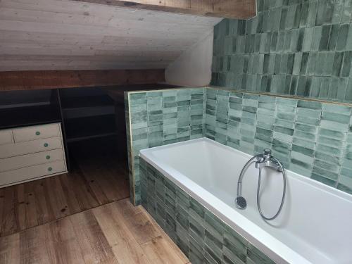 a bathroom with a bath tub with green tiles at Maison 8 personnes in Mézos