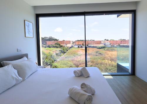 a bedroom with a large window with towels on a bed at Villa Pingau in Vila Nova de Gaia