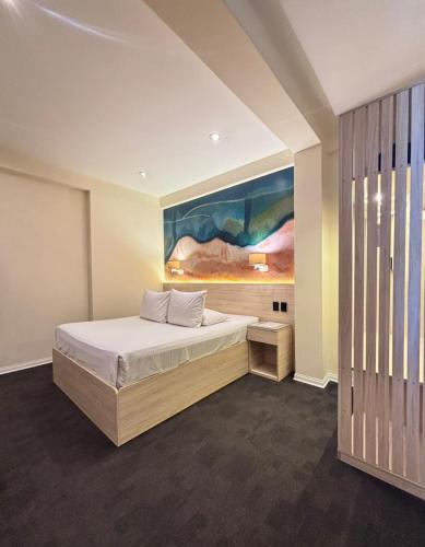 a bedroom with a bed and a painting on the wall at Hotel Gran Palma Piura in Piura