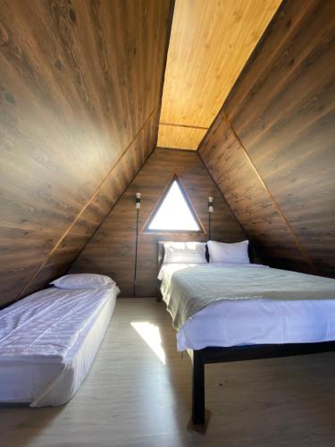 two beds in a attic room with a window at Baet Home in Bayetovka