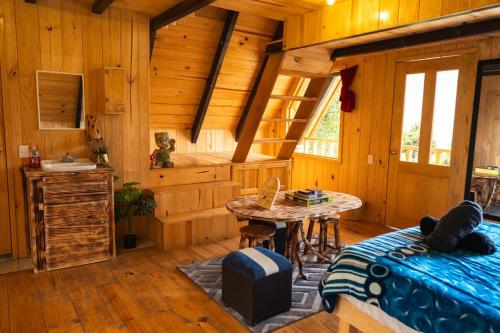 a room with a bed and a table in a cabin at El Paraje Cabaña 2 in San Andrés Paxtlán