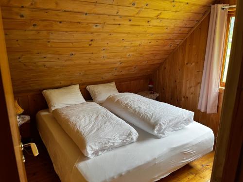 a bed in a wooden room with two pillows on it at Enesi holiday house in Hestenesøyra