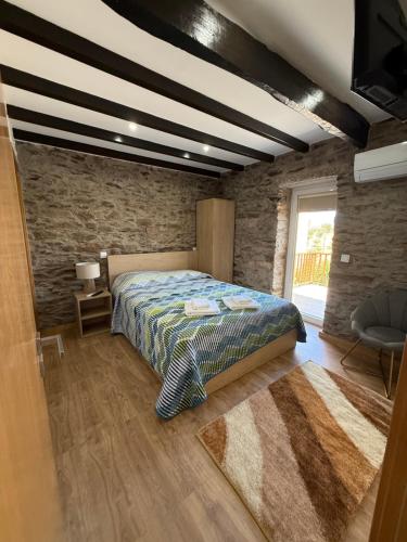 a bedroom with a bed and a stone wall at A casa do Avô Cruzes in Cerejais