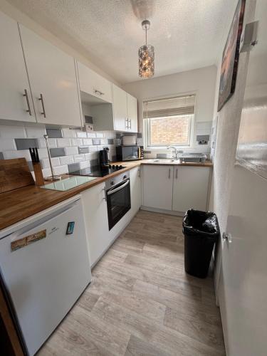 a kitchen with white cabinets and a black appliance at 121 Sunbeach - Two bed Chalet at Scratby - Sleeps 5, pet friendly - plus WiFi, bed linen and towels included - FREE swimming passes and Entertainment - Only 300m from the beach in Scratby