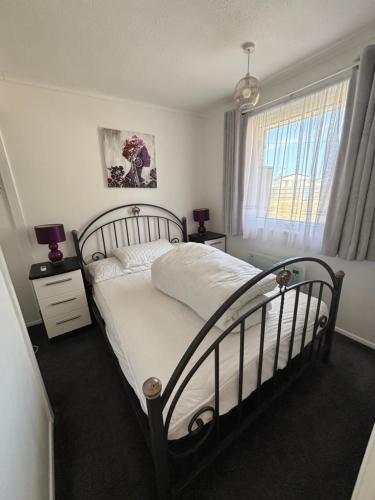 a bedroom with a black and white bed and a window at 121 Sunbeach - Two bed Chalet at Scratby - Sleeps 5, pet friendly - plus WiFi, bed linen and towels included - FREE swimming passes and Entertainment - Only 300m from the beach in Scratby