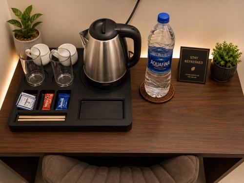 a table with a coffee maker and a bottle of water at Hotel Namah Prime Near By Chanda Nagar Ameenpur Road in Hyderabad