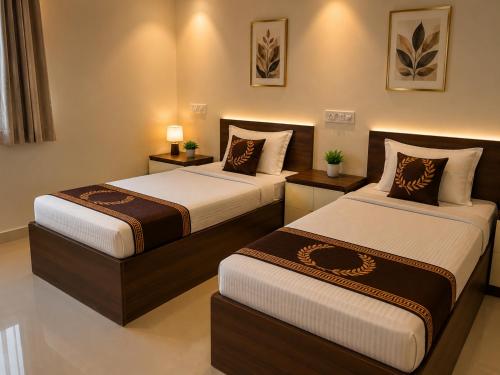 two beds in a hotel room with two lamps at Hotel Namah Prime Near By Chanda Nagar Ameenpur Road in Hyderabad