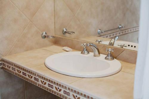 een badkamer met een witte wastafel en een spiegel bij Hotel del Virrey in Luján