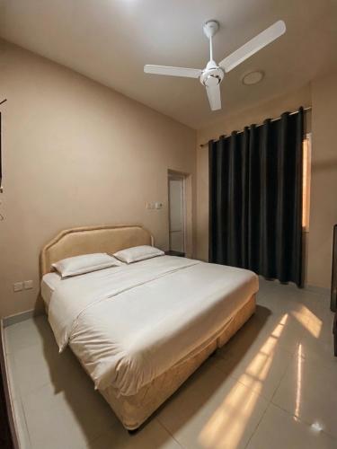 a bed in a bedroom with a ceiling fan at RED algarbeia in Salalah