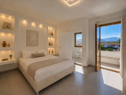 a white bedroom with a large bed and a bathroom at Hotel Cala d'Oro - Hotel a pochi minuti dal mare di Cala Liberotto in Cala Liberotto