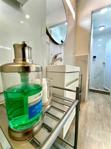 a container of green liquid on a shelf in a bathroom at Barrio Inn Padre Mier Hostal & Suites in Monterrey