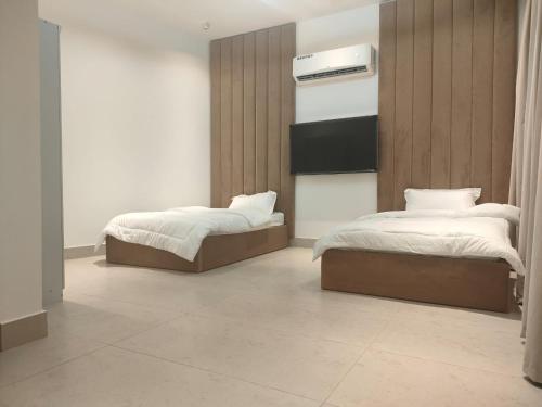 a bedroom with two beds and a heater on the wall at Alpha Holiday Home in Barka