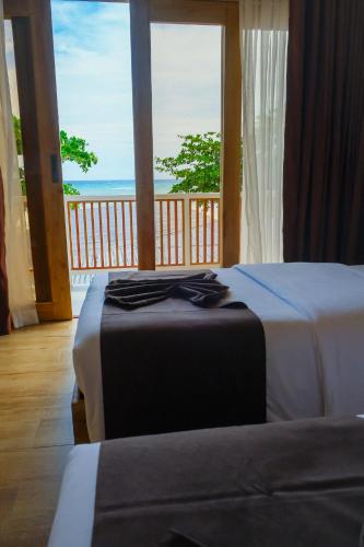 a bedroom with two beds and a view of the ocean at Soluna Siquijor Boutique Resort in San Juan