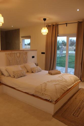 a bedroom with a large bed with a large window at Monte do Raposo Country House in Monte da Pedra Alva