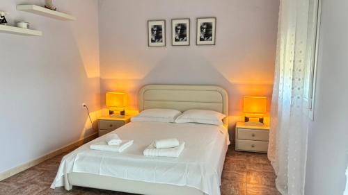 a bedroom with a white bed with two lamps at Folini House in Magaziá