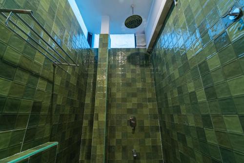 a bathroom with a shower with green tiled walls at Versailles Backpacker Hostel in Pondicherry