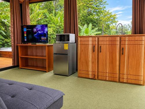 a kitchen with wooden cabinets and a tv and a refrigerator at Nido de Cristal con Jacuzzi y AC in Agua Azul