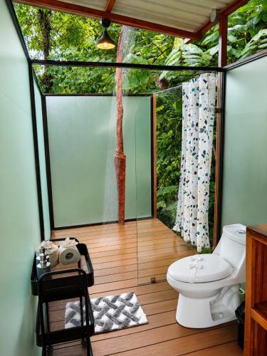 a bathroom with a toilet and a tree outside at Nido de Cristal con Jacuzzi y AC in Agua Azul