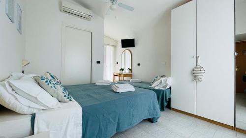 a white bedroom with a bed with a blue blanket at Albergo Villa Denny in Rimini