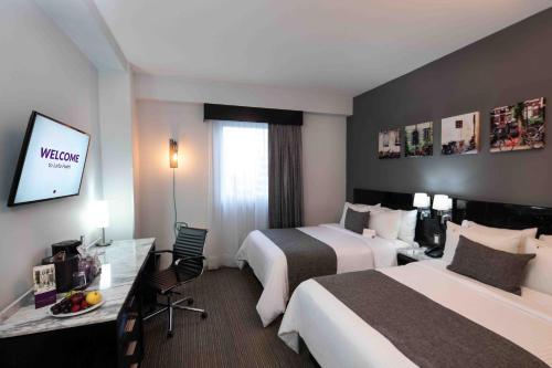 a hotel room with two beds and a flat screen tv at LaiLa Hotel Mexico City Reforma in Mexico City