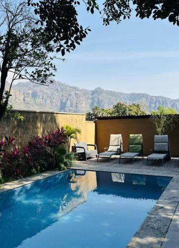 a swimming pool with lounge chairs and mountains in the background at Sierra Central By Chic Hotel Group in Tepoztlán