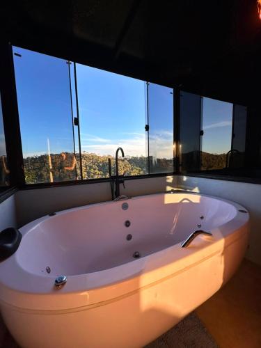 a large white bath tub in a room with windows at Chalé dos Manacás 02 Venda Nova Alto Colina ES in Venda Nova do Imigrante
