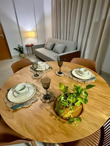 a wooden table with plates and wine glasses on it at Flat Aconchego no Setor Oeste a 50m do Lago das Rosas, apto novo in Goiânia