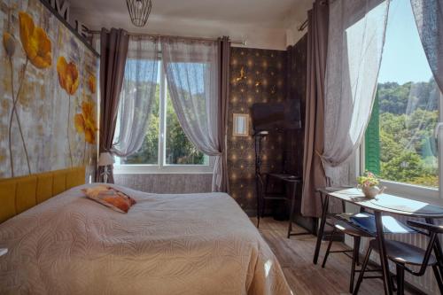 ein Schlafzimmer mit einem Bett, einem Tisch und einem Fenster in der Unterkunft Studio Malou - Cosy, grande terrasse et vue rivière in Olliergues
