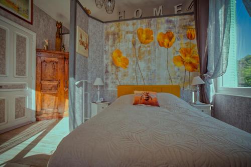 ein Schlafzimmer mit einem großen Bett mit Blumentapete in der Unterkunft Studio Malou - Cosy, grande terrasse et vue rivière in Olliergues