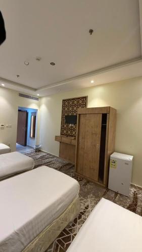 a bedroom with two beds and a desk in it at فندق جوهرة الحجاز ريع بخش توصيل من والي الحرم مجاني in An Naqāʼ